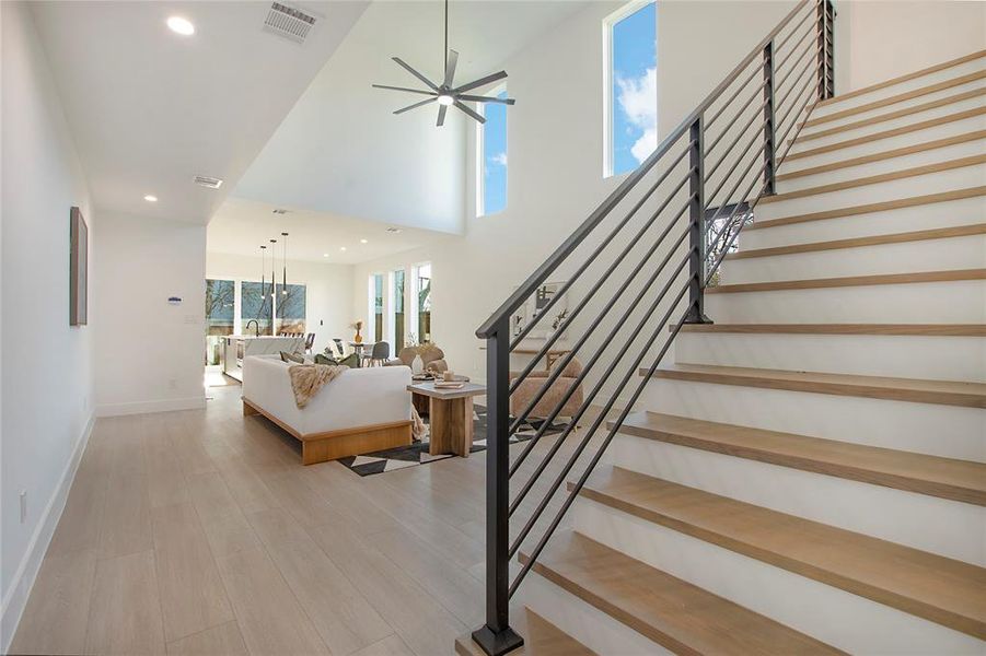 Staircase with wood-type flooring and ceiling fan with notable chandelier