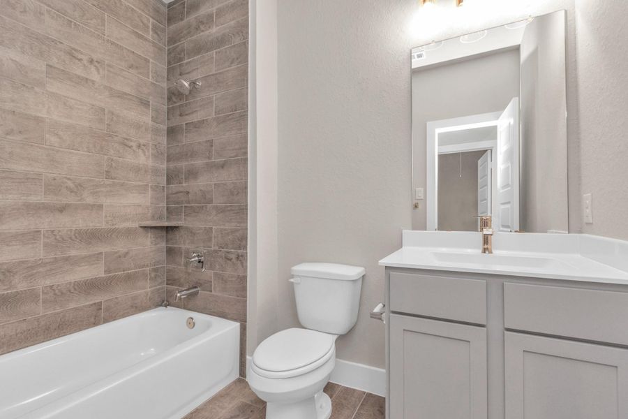 Experience sophistication in the secondary bathroom, where tile flooring complements a bath/shower combo with tile surround. Light wood cabinets complete with a beautiful light countertop, vanity lights, and modern hardware enhances the space for a truly inviting ambiance. Sample photo of completed home with similar floor plan. Actual colors and selections may vary. Experience sophistication in the secondary bathroom, where tile flooring complements a bath/shower combo with tile surround. Light wood cabinets complete with a beautiful light countertop, vanity lights, and modern hardware enhances the space for a truly inviting ambiance. Sample photo of completed home with similar floor plan. Actual colors and selections may vary.