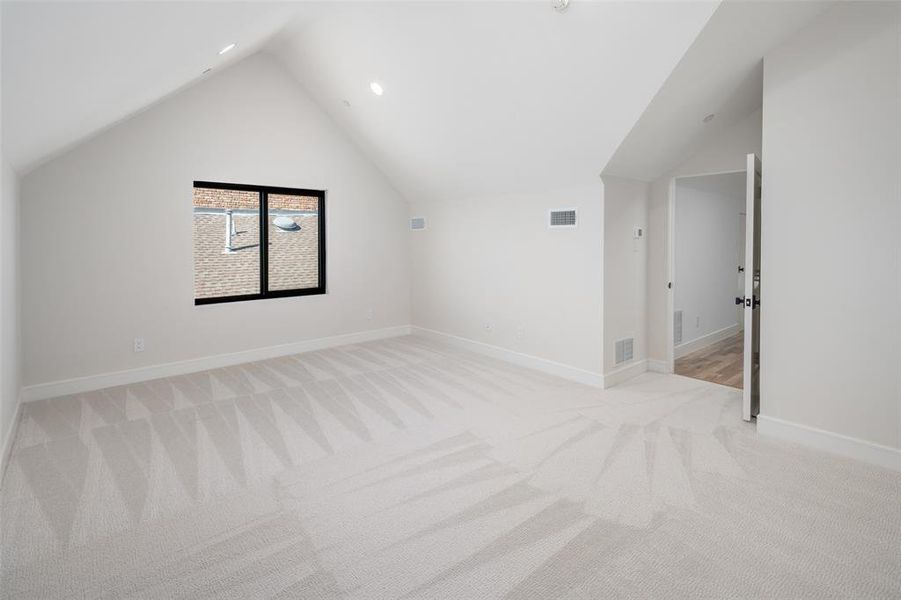 Bonus room featuring light colored carpet and vaulted ceiling