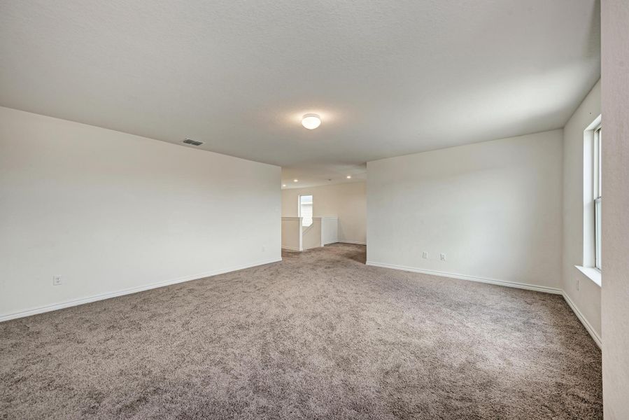 A spacious, neutral-toned family room offers ample living space with plush carpeting throughout.