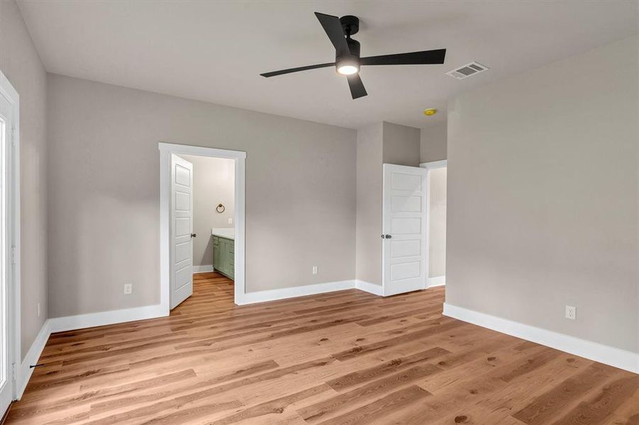 Unfurnished bedroom featuring light wood finished floors, a ceiling fan, and ensuite bathroom