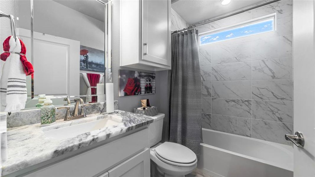 Full bathroom with vanity with extensive cabinet space, toilet, and shower / bath combo with shower curtain