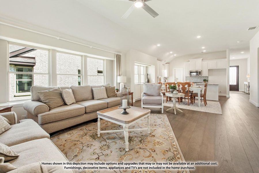 Open-concept living room with vaulted ceiling, hardwood floors, and view into dining area and kitchen Open-concept living room with vaulted ceiling, hardwood floors, and view into dining area and kitchen