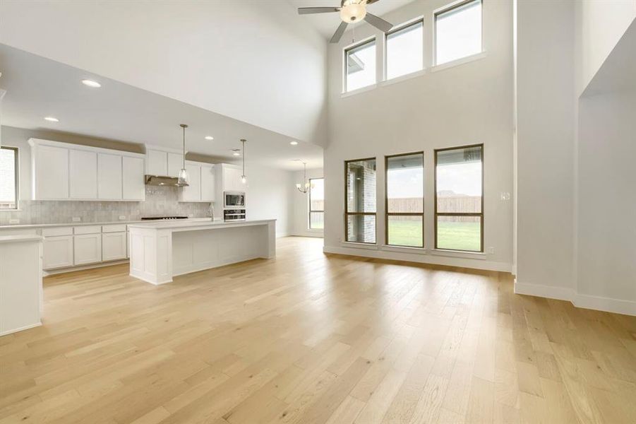 Spacious living area featuring high vaulted ceilings, light wood-finish flooring, and a contemporary kitchen Spacious living area featuring high vaulted ceilings, light wood-finish flooring, and a contemporary kitchen