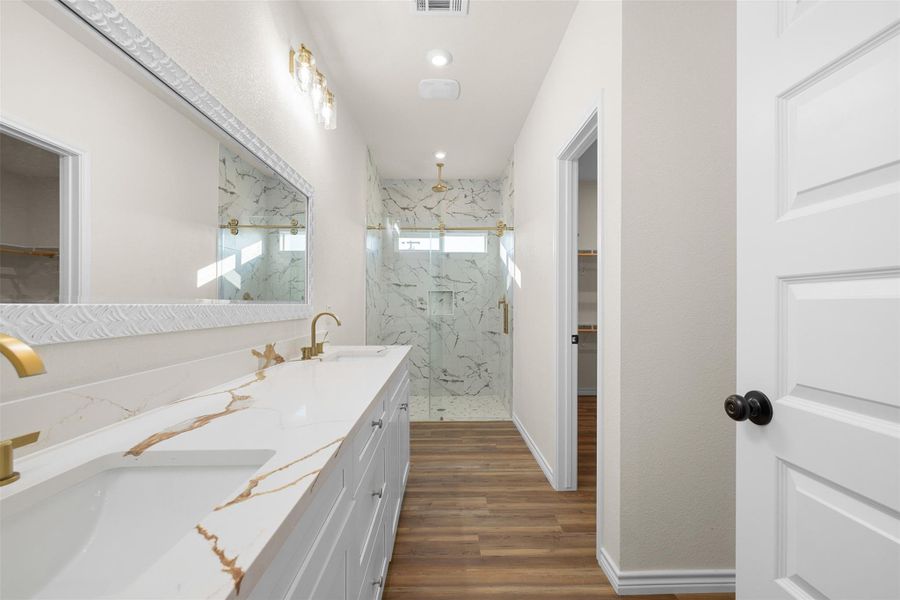 Bathroom with a spacious closet, a marble finish shower, dark wood finished floors, double vanity, and recessed lighting Bathroom with a spacious closet, a marble finish shower, dark wood finished floors, double vanity, and recessed lighting