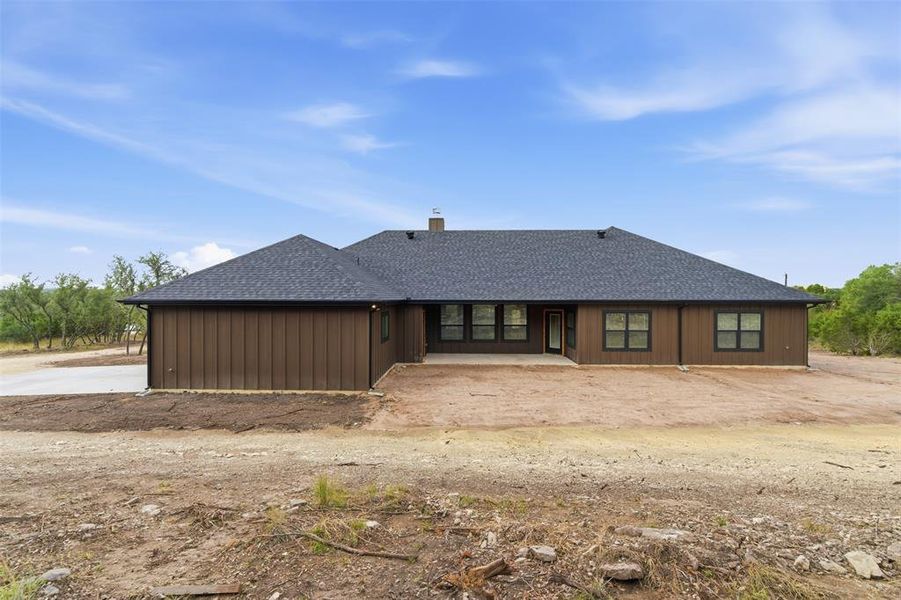View of front of home featuring roof with shingles, a patio area, and a chimney View of front of home featuring roof with shingles, a patio area, and a chimney