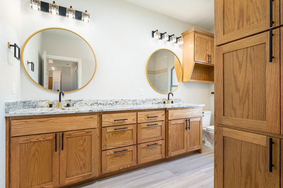 Bathroom featuring double vanity and light wood finished floors Bathroom featuring double vanity and light wood finished floors