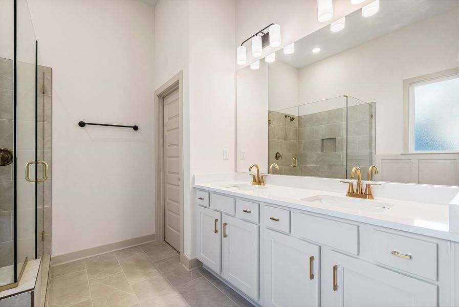 Bathroom with double vanity, light tile patterned floors, and a shower stall