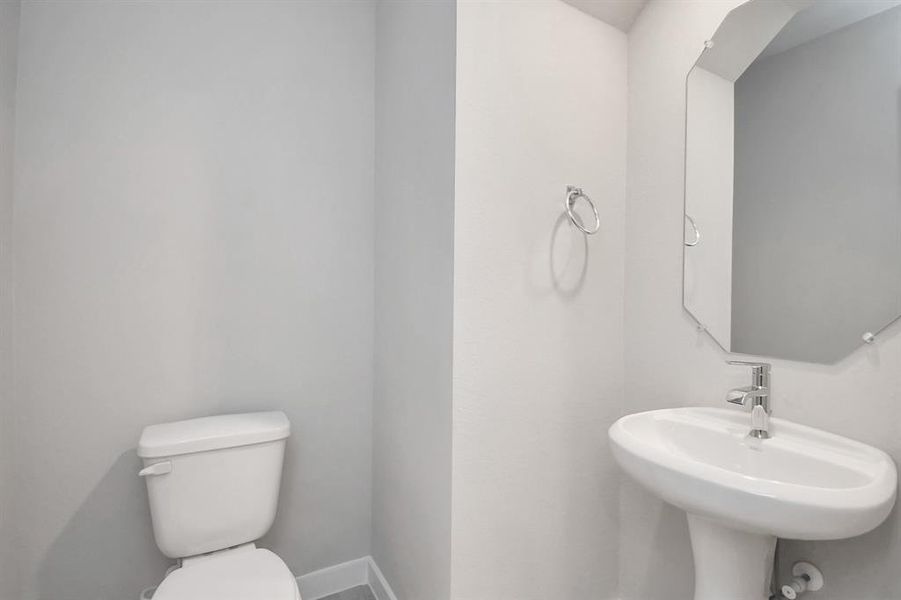 Delightful half bathroom featuring a sophisticated 5-panel door, upgraded pedestal sink, contemporary hardware, and bright recessed lights.