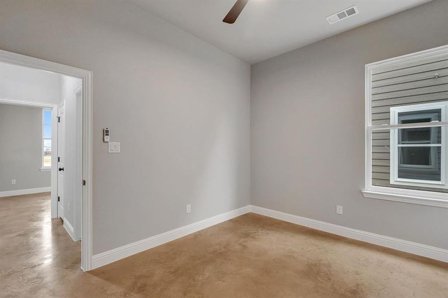 Unfurnished room with finished concrete floors and ceiling fan
