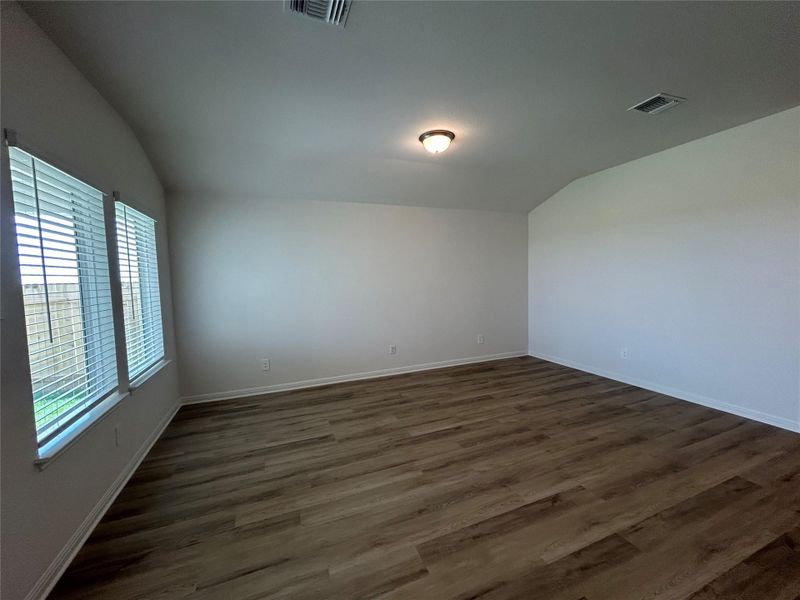 Empty room featuring vaulted ceiling and dark wood-style flooring Empty room featuring vaulted ceiling and dark wood-style flooring