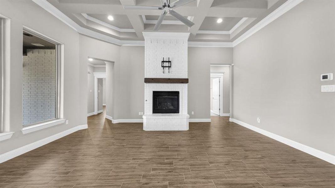 L living room featuring coffered ceiling, a brick fireplace, ceiling fan, and beamed ceiling