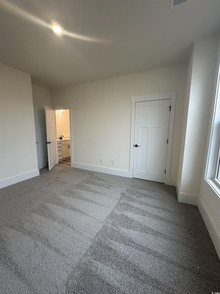 Unfurnished bedroom with connected bathroom and light colored carpet