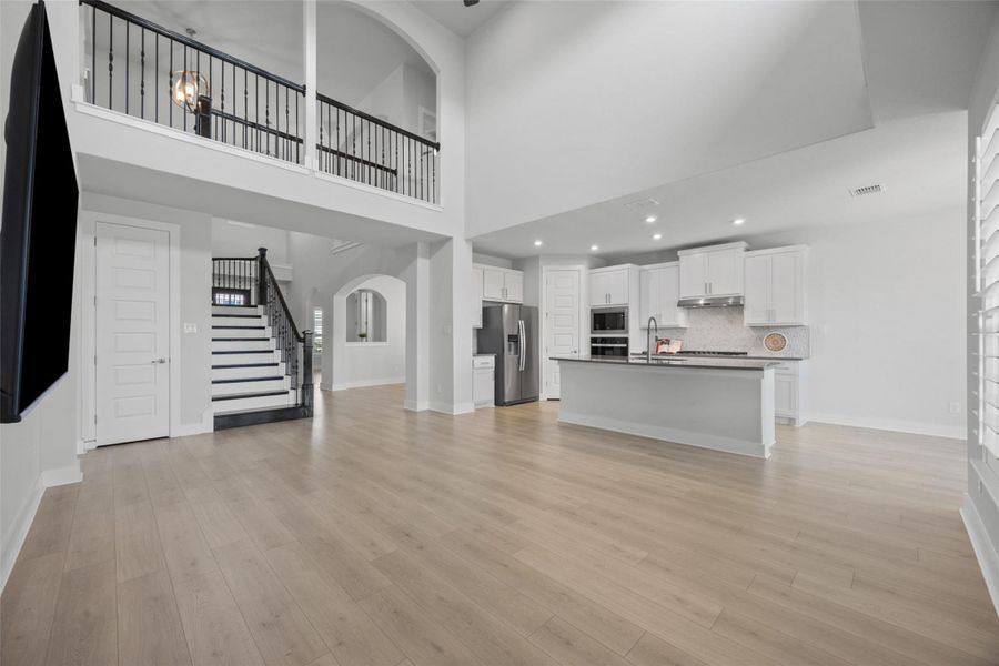 An open-concept living area boasts high ceilings, a grand staircase, and a contemporary kitchen with abundant cabinet space.