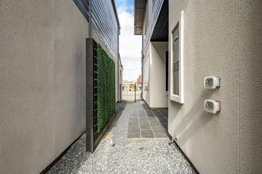 View of side of home with stucco siding and a gate