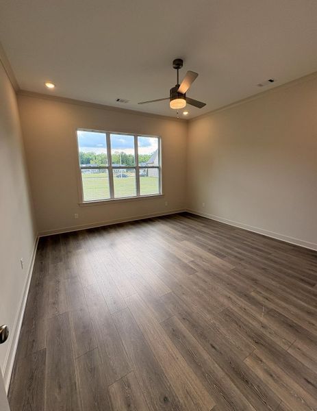 Spacious room featuring wood-finish flooring, a multi-pane window, crown molding, a ceiling fan with integrated lighting, and recessed ceiling lights