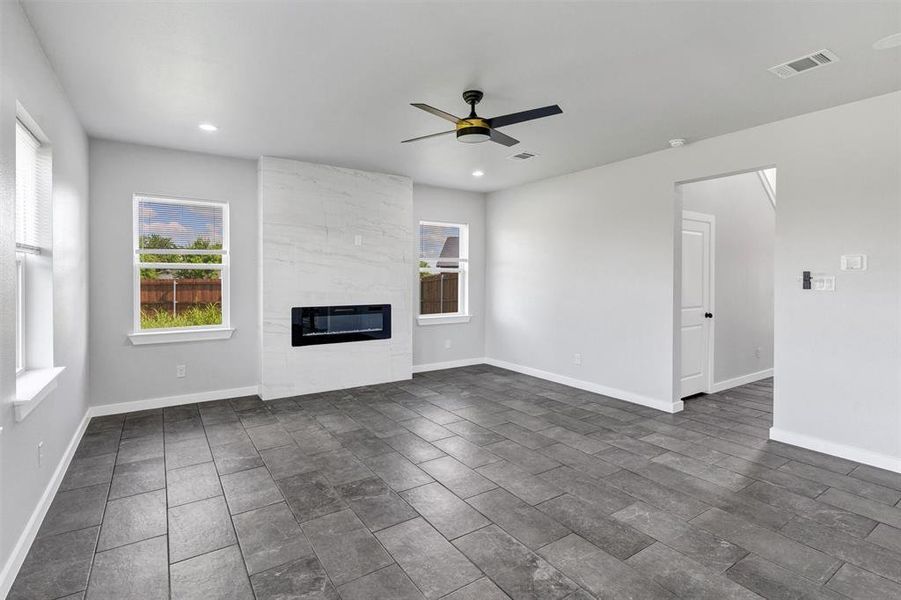 Unfurnished living room featuring ceiling fan, a fireplace, recessed lighting, baseboards, and heating unit