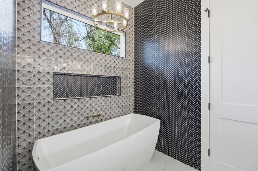 Bathroom with a freestanding tub, hanging lights, and tile walls