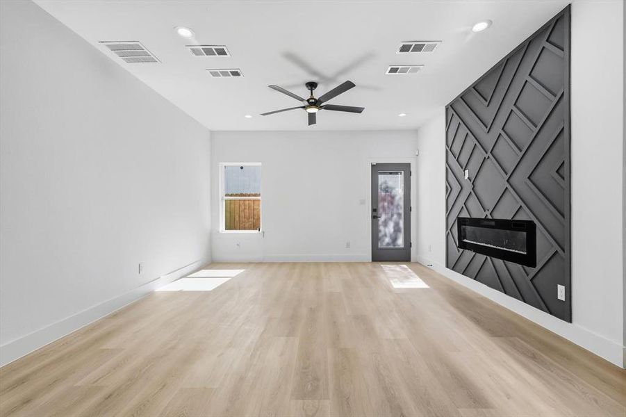 Unfurnished living room with a fireplace, a ceiling fan, light wood-style flooring, and recessed lighting Unfurnished living room with a fireplace, a ceiling fan, light wood-style flooring, and recessed lighting