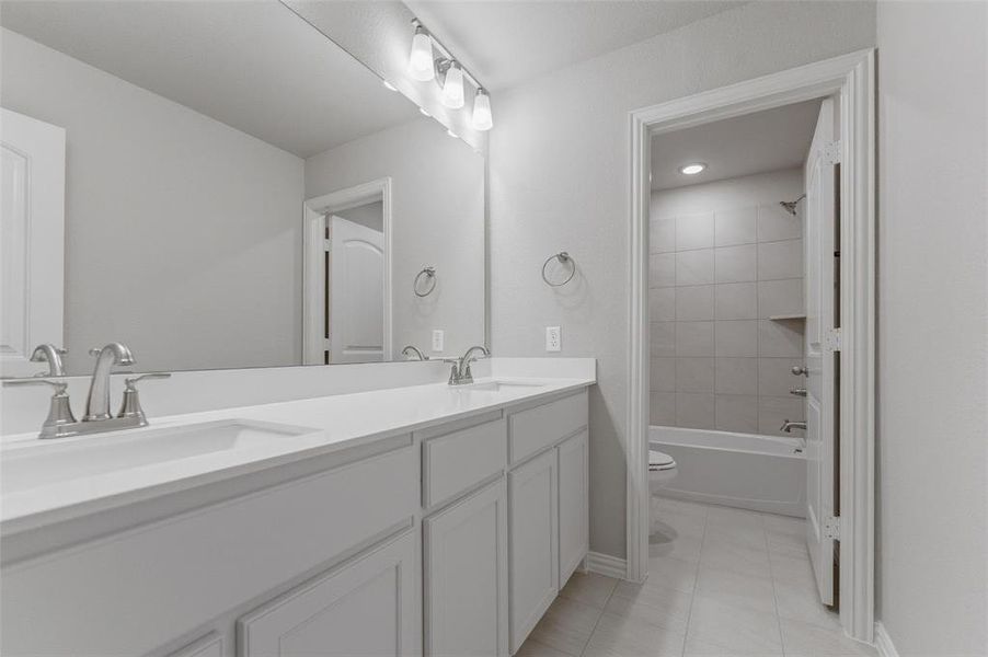 Bathroom featuring double vanity, shower / bathtub combination, and light tile patterned floors