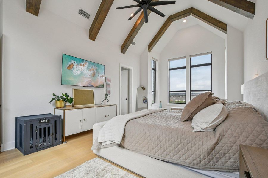 This bedroom features a vaulted ceiling with exposed wooden beams, large windows providing expansive views, and light hardwood flooring This bedroom features a vaulted ceiling with exposed wooden beams, large windows providing expansive views, and light hardwood flooring