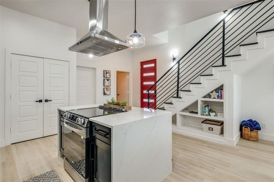 Kitchen featuring light hardwood / wood-style floors, island range hood, light stone countertops, stainless steel electric range oven, and hanging light fixtures