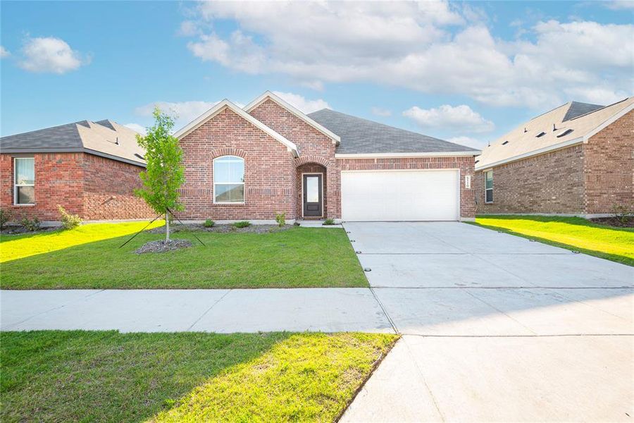 Brick-clad single-story residence featuring a two-car garage, arched entry, and a concrete driveway Brick-clad single-story residence featuring a two-car garage, arched entry, and a concrete driveway