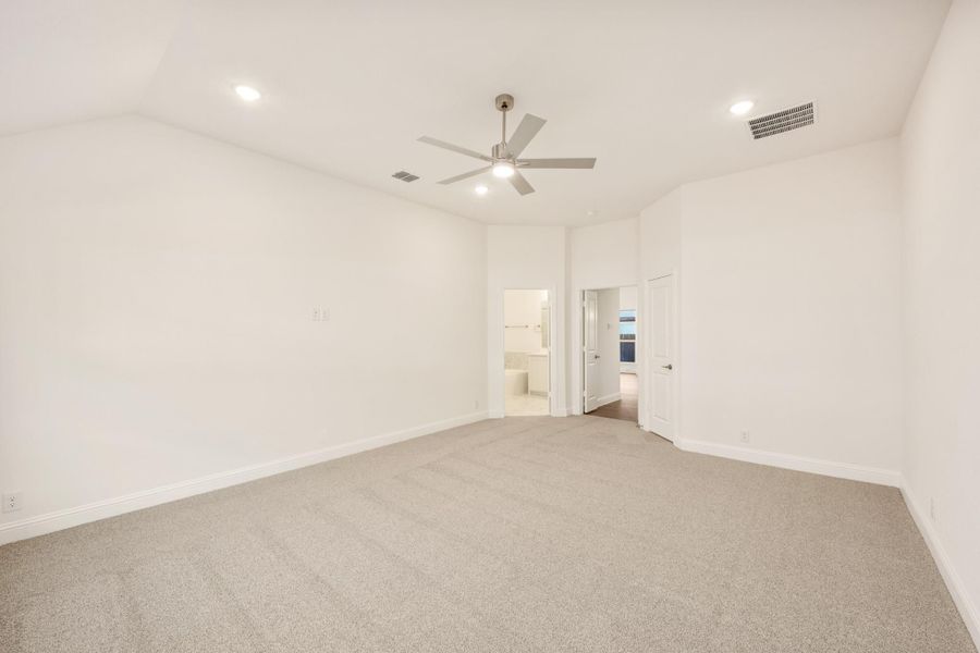 Empty bedroom with beige carpet, ceiling fan, white walls, and open door to ensuite bathroom Empty bedroom with beige carpet, ceiling fan, white walls, and open door to ensuite bathroom
