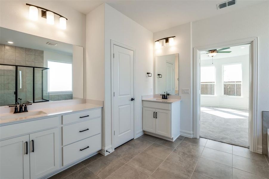 Bathroom with vanity, a shower with shower door, a healthy amount of sunlight, and ceiling fan