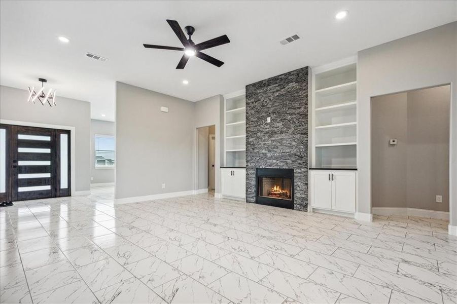 Unfurnished living room with marble finish floor, baseboards, built in features, and a ceiling fan