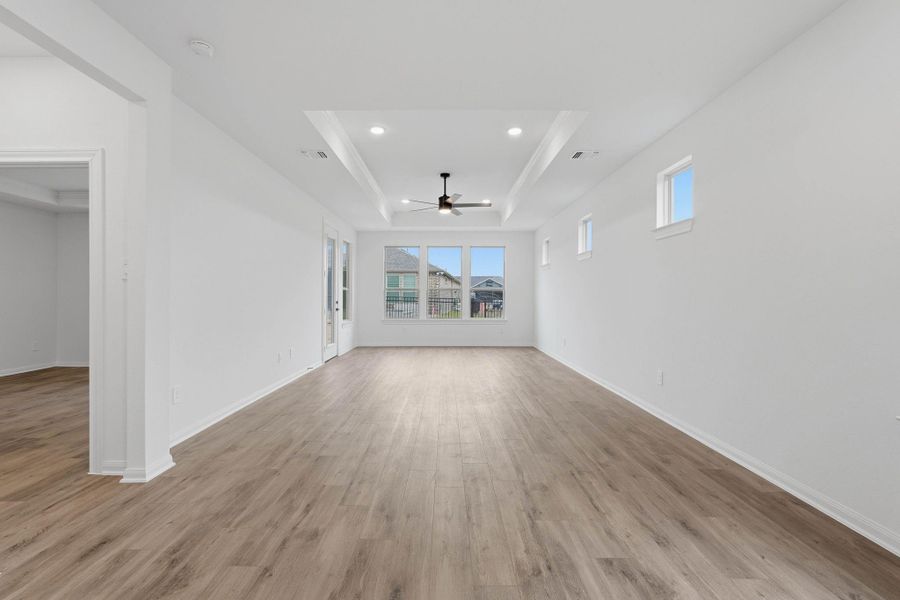 The living area feels open and relaxed, featuring light flooring, recessed lighting, a modern ceiling fan, and large windows that bring the outdoors in.