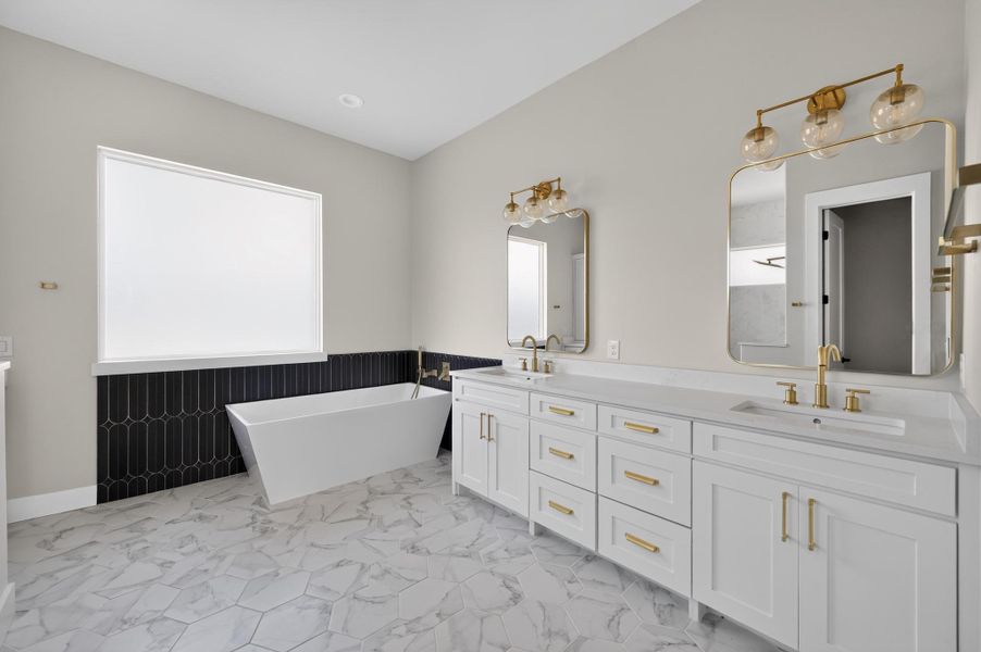 Elegant marble-patterned tile flooring anchors this washroom featuring a freestanding tub and double vanity.