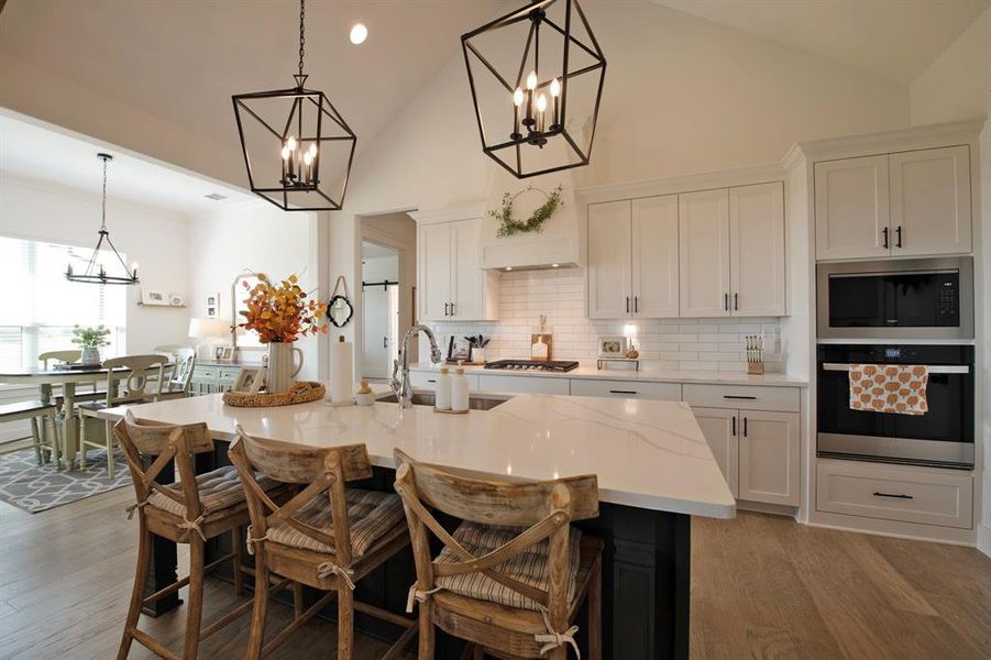Kitchen featuring appliances with stainless steel finishes, decorative backsplash, a chandelier, white cabinets, and high vaulted ceiling