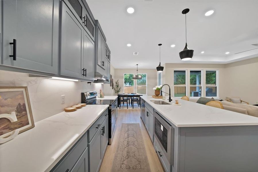 Modern kitchen featuring light gray cabinetry with black hardware, white countertops, stainless steel appliances, and recessed lighting Modern kitchen featuring light gray cabinetry with black hardware, white countertops, stainless steel appliances, and recessed lighting