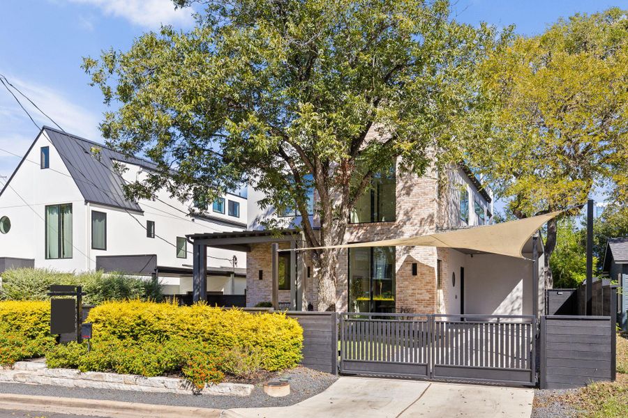 View of front of home featuring brick siding, a fenced front yard, a gate, and stucco siding View of front of home featuring brick siding, a fenced front yard, a gate, and stucco siding