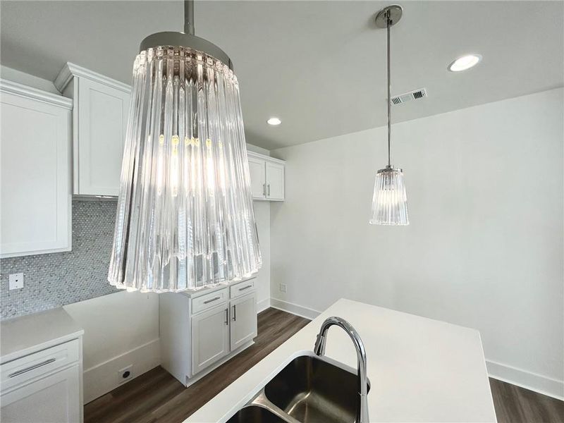 Kitchen featuring hanging light fixtures, dark hardwood / wood-style flooring, and white cabinetry