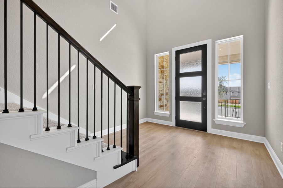 Entrance foyer with light wood finished floors, stairs, and a towering ceiling
