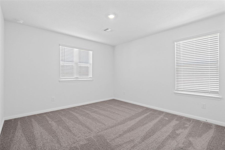 Secondary bedroom, pictured here, features plush carpeting, neutral paint tones, recessed lighting, large windows with privacy blinds, and a walk-in closet.