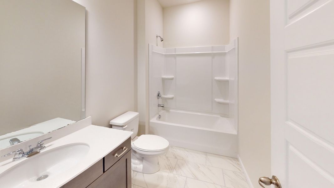 Guest bath features quartz countertops and walk-in shower.