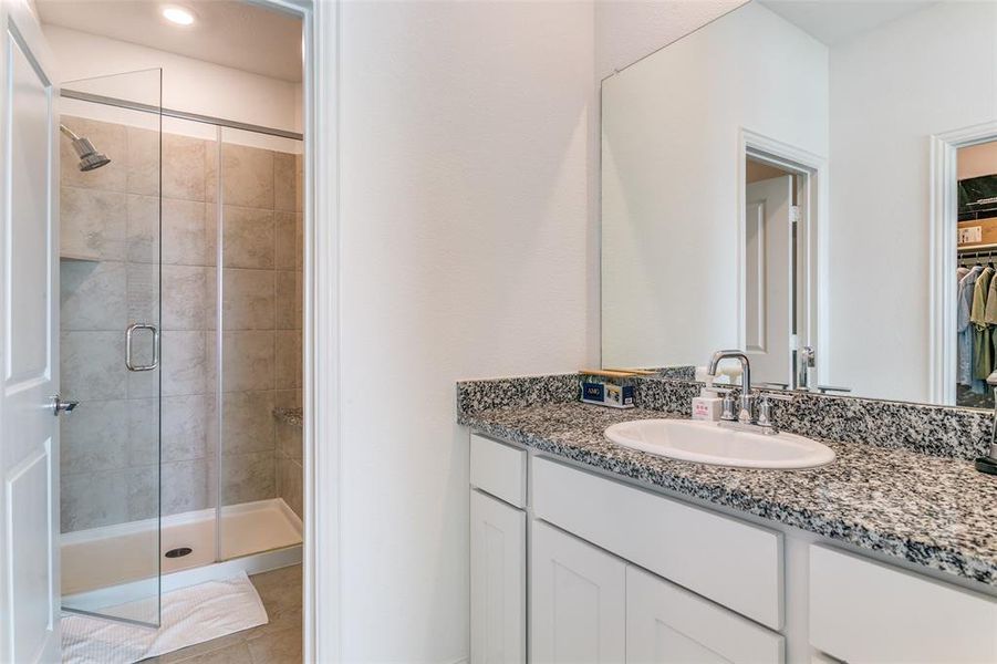 Bathroom featuring a stall shower, vanity, a spacious closet, and light tile patterned floors