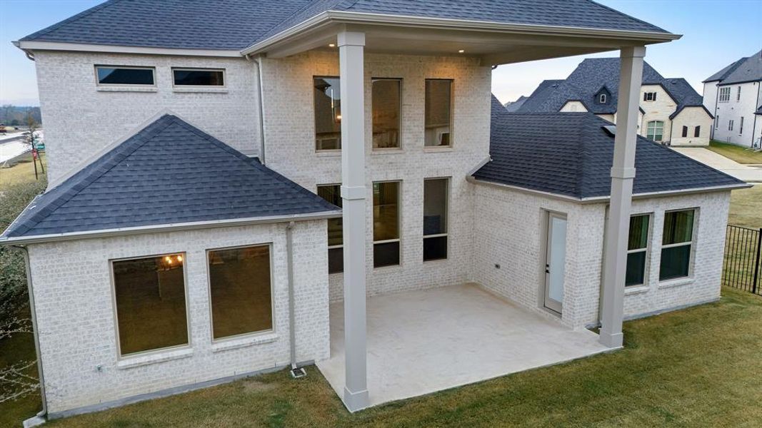 Rear view of house with a patio, brick siding, roof with shingles, and a lawn Rear view of house with a patio, brick siding, roof with shingles, and a lawn