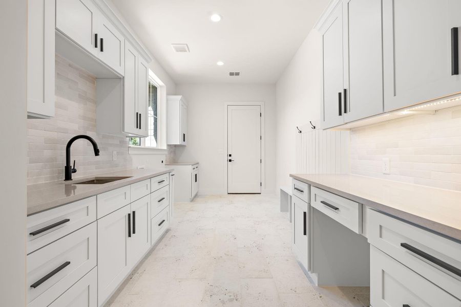 Kitchen featuring white cabinetry, light countertops, and a sink