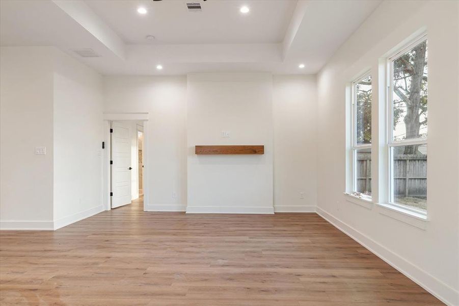 Generously sized living area with a view of the backyard, featuring a modern ceiling fan, trayed ceiling and recessed lighting to match your mood.