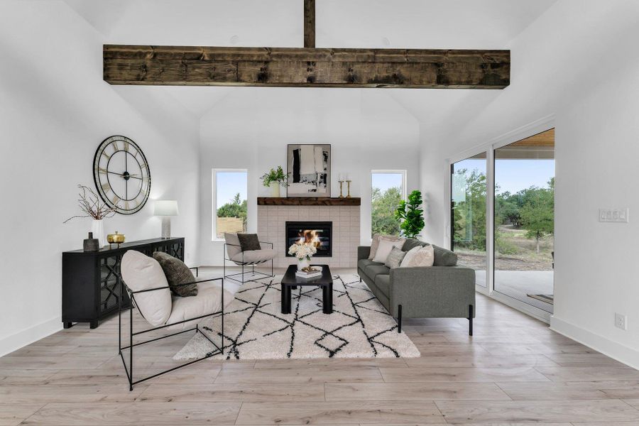Living room with a brick fireplace, beamed ceiling, and light wood-type flooring