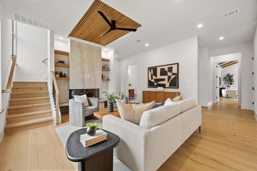 Rich wood flooring and a modern stone fireplace define this light-filled living area.