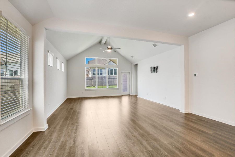 Spacious interior featuring a vaulted ceiling with a ceiling fan, recessed lighting, and wood-finish flooring