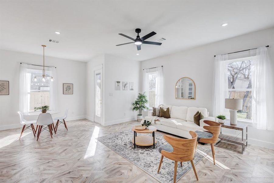 Living room with ceiling fan with notable chandelier and light parquet floors