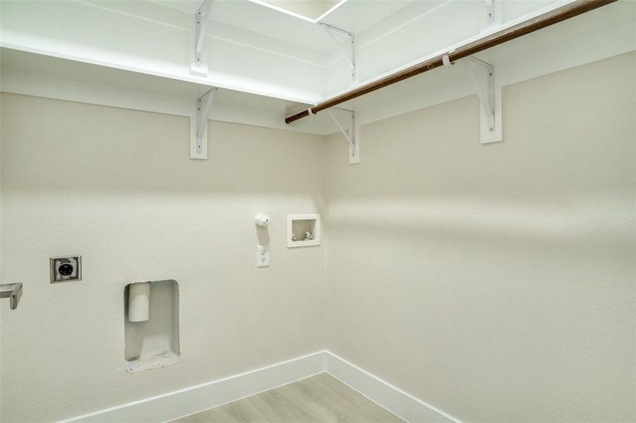 Clothes washing area with washer hookup, hookup for an electric dryer, laundry area, baseboards, and light wood-style floors