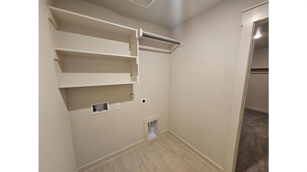 Dedicated utility space featuring built-in shelving, a hanging rod, and light wood-finish flooring Dedicated utility space featuring built-in shelving, a hanging rod, and light wood-finish flooring