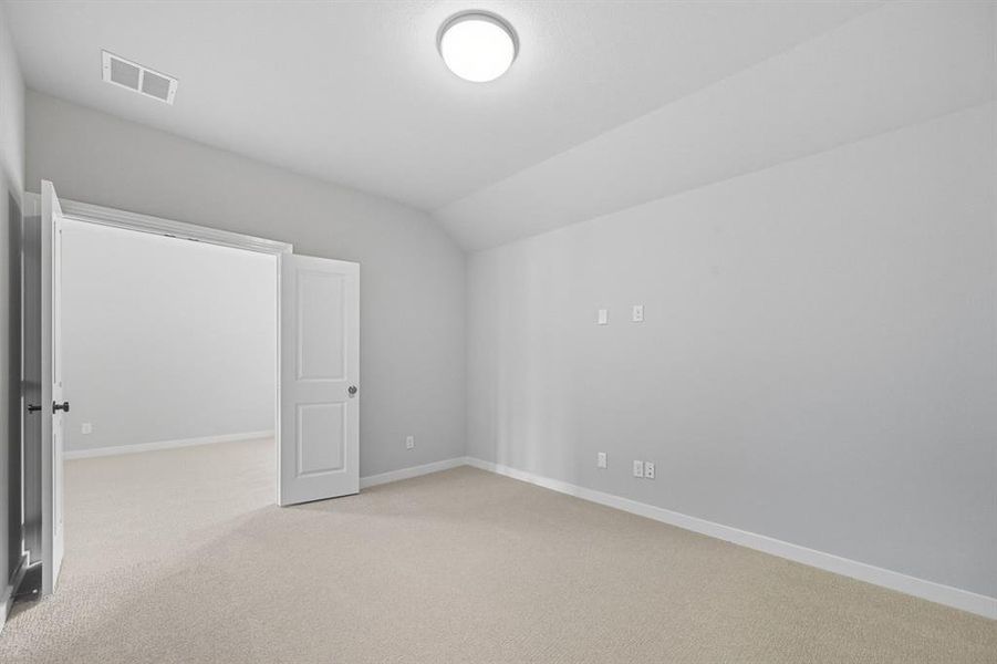 Unfurnished bedroom featuring vaulted ceiling and light colored carpet